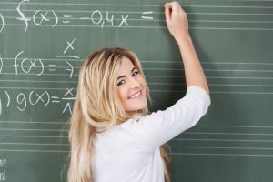 Schülerin löst Matheaufgaben an der Tafel